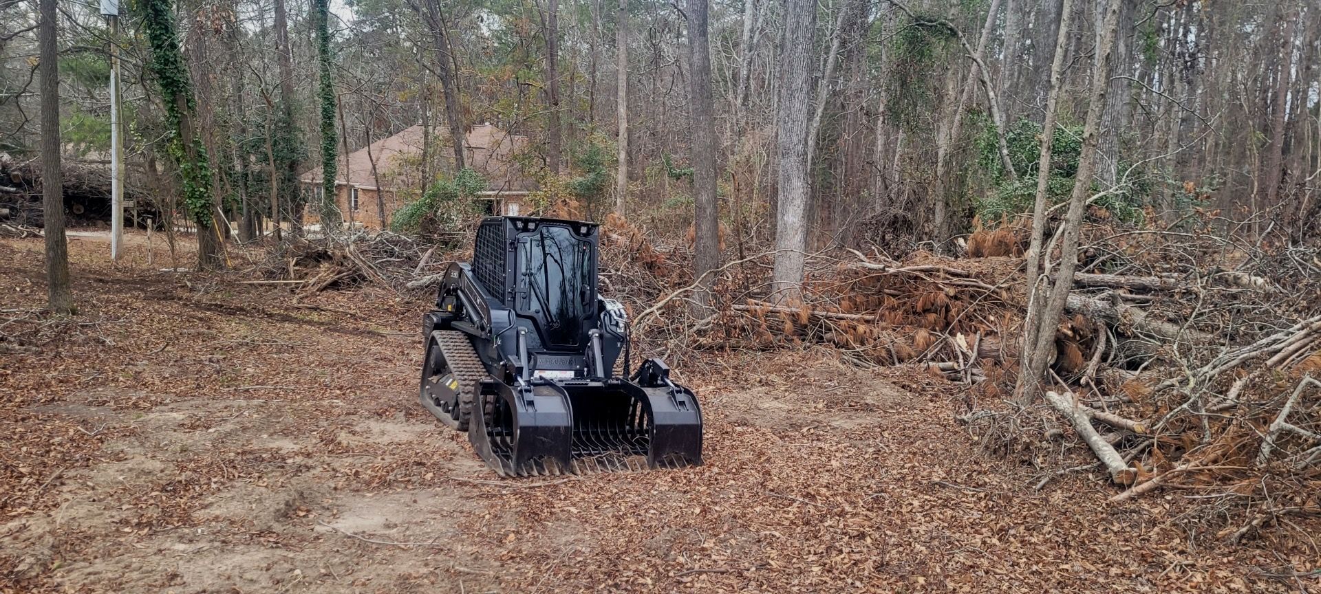 A black tractor is driving through a lush green forest.