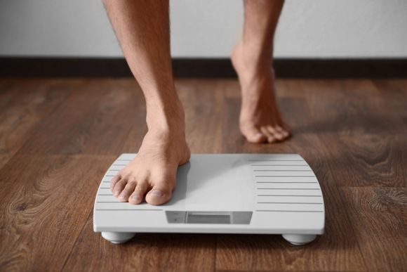closeup of feet stepping onto scale for weight loss