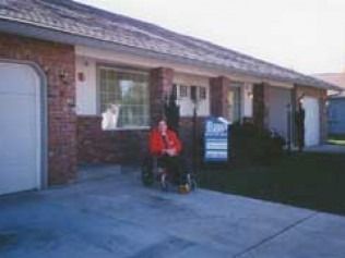 Family standing in front of a house, holding a sign.