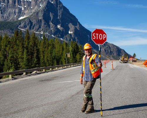 worker on road holding stop sign