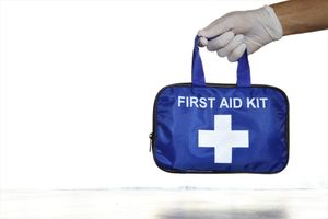 hand wearing white glove holding first aid kit