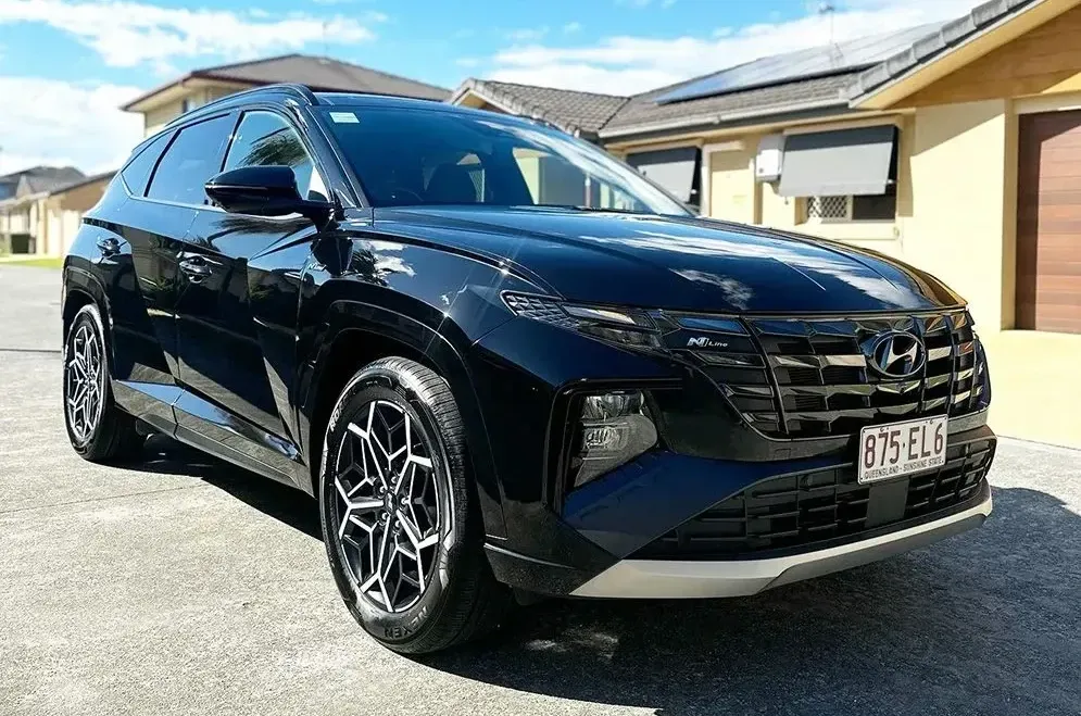 A Black Car Is Parked In Front Of A House — Remedy Mobile Car Detailing in Robina, QLD