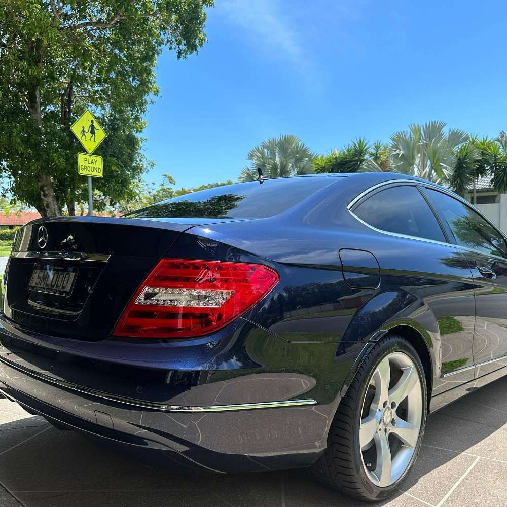 A Black Mercedes is Parked in Front of a School Crossing Sign — Remedy Mobile Car Detailing in Gold Coast, QLD