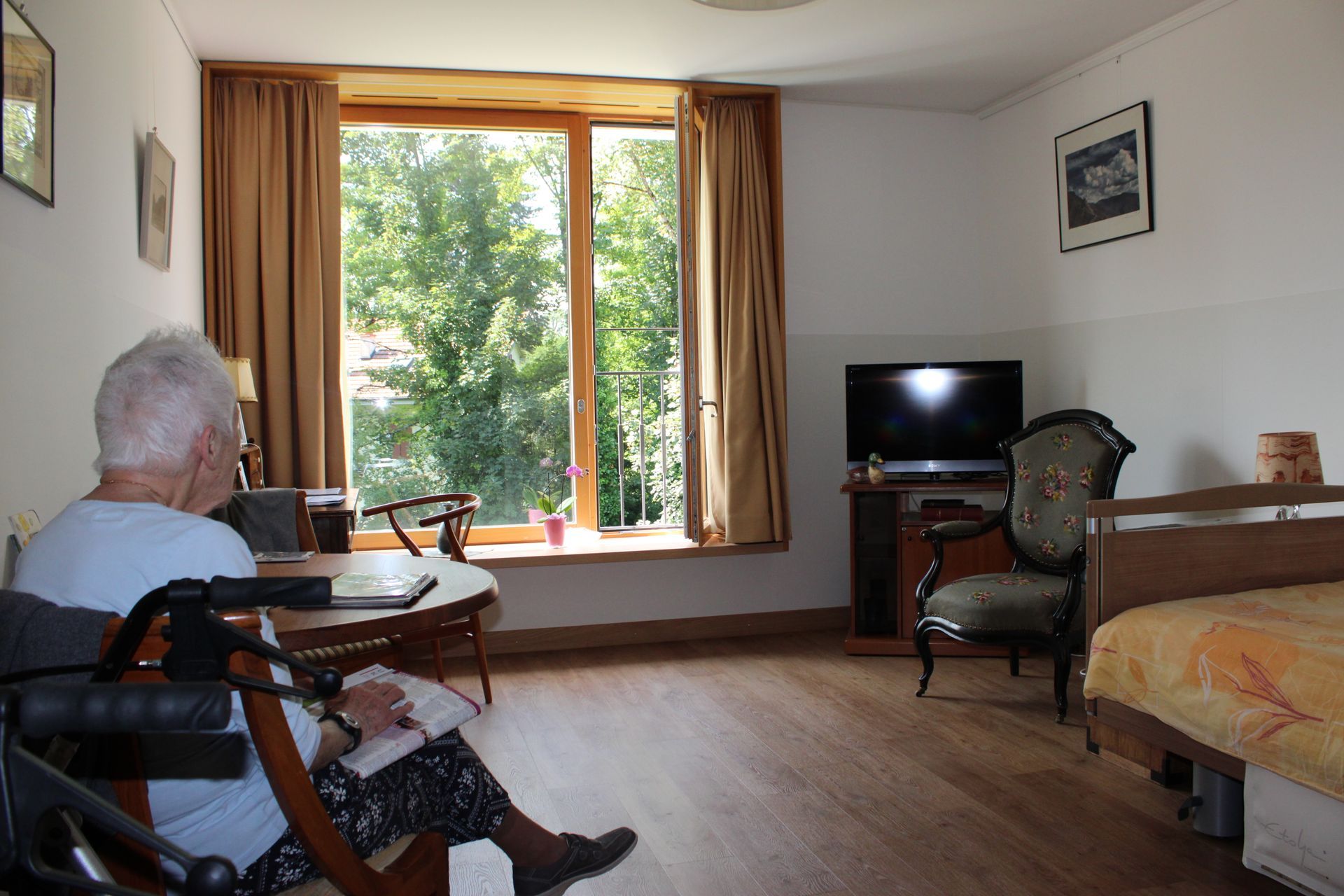 Un homme en fauteuil roulant est assis dans un salon à côté d'un lit.