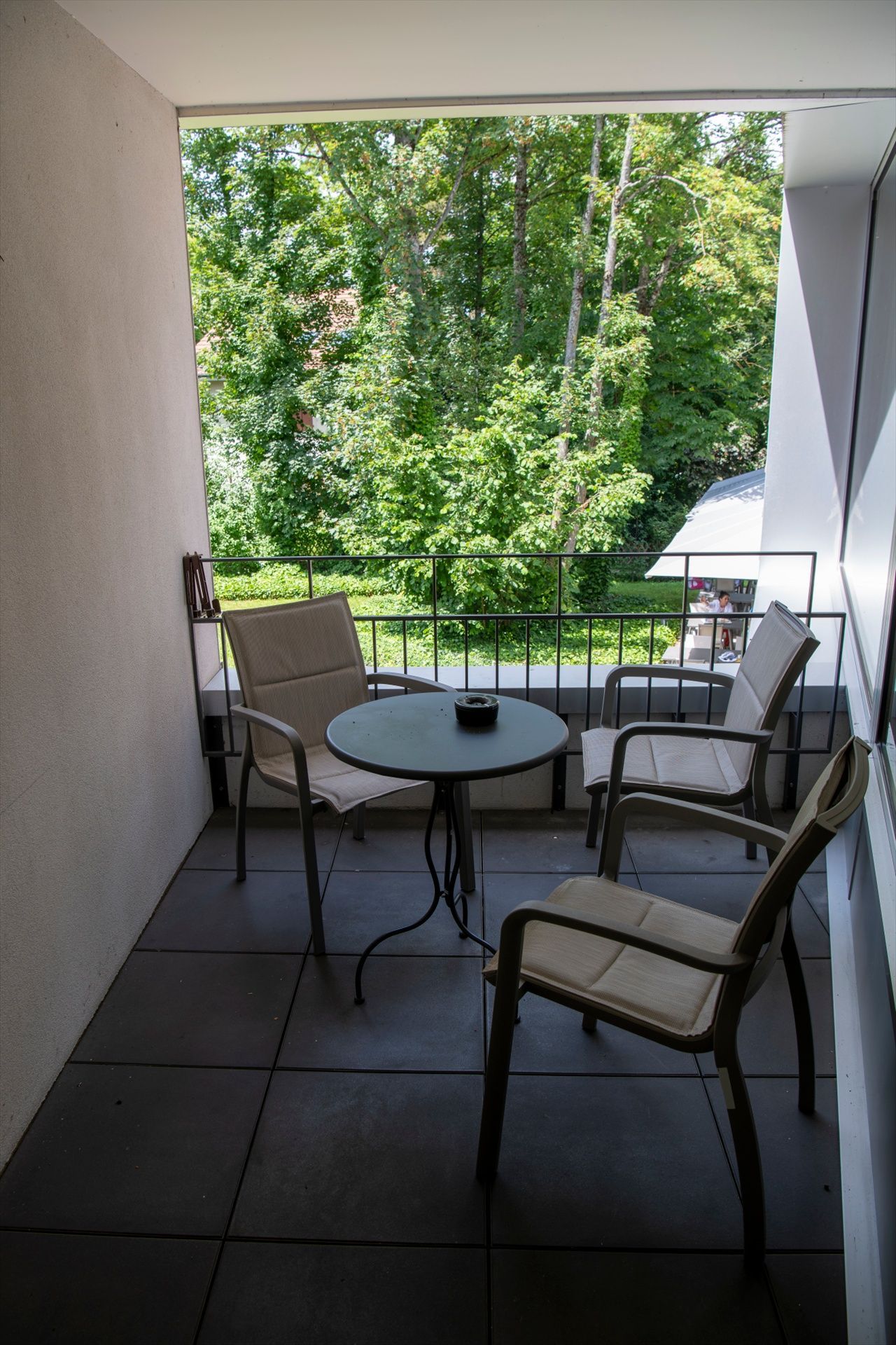 Un balcon avec une table et des chaises et des arbres en arrière-plan.