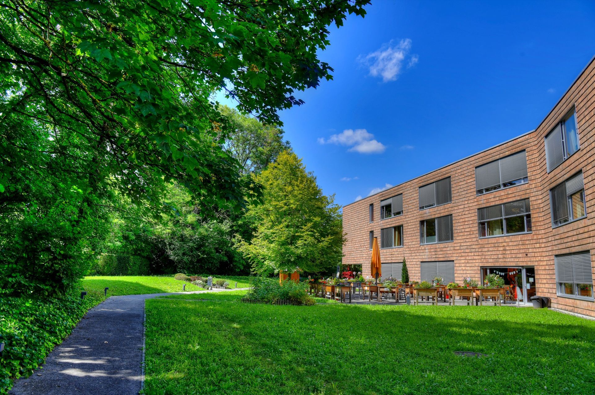 Un grand bâtiment en briques avec une pelouse verte luxuriante devant lui.