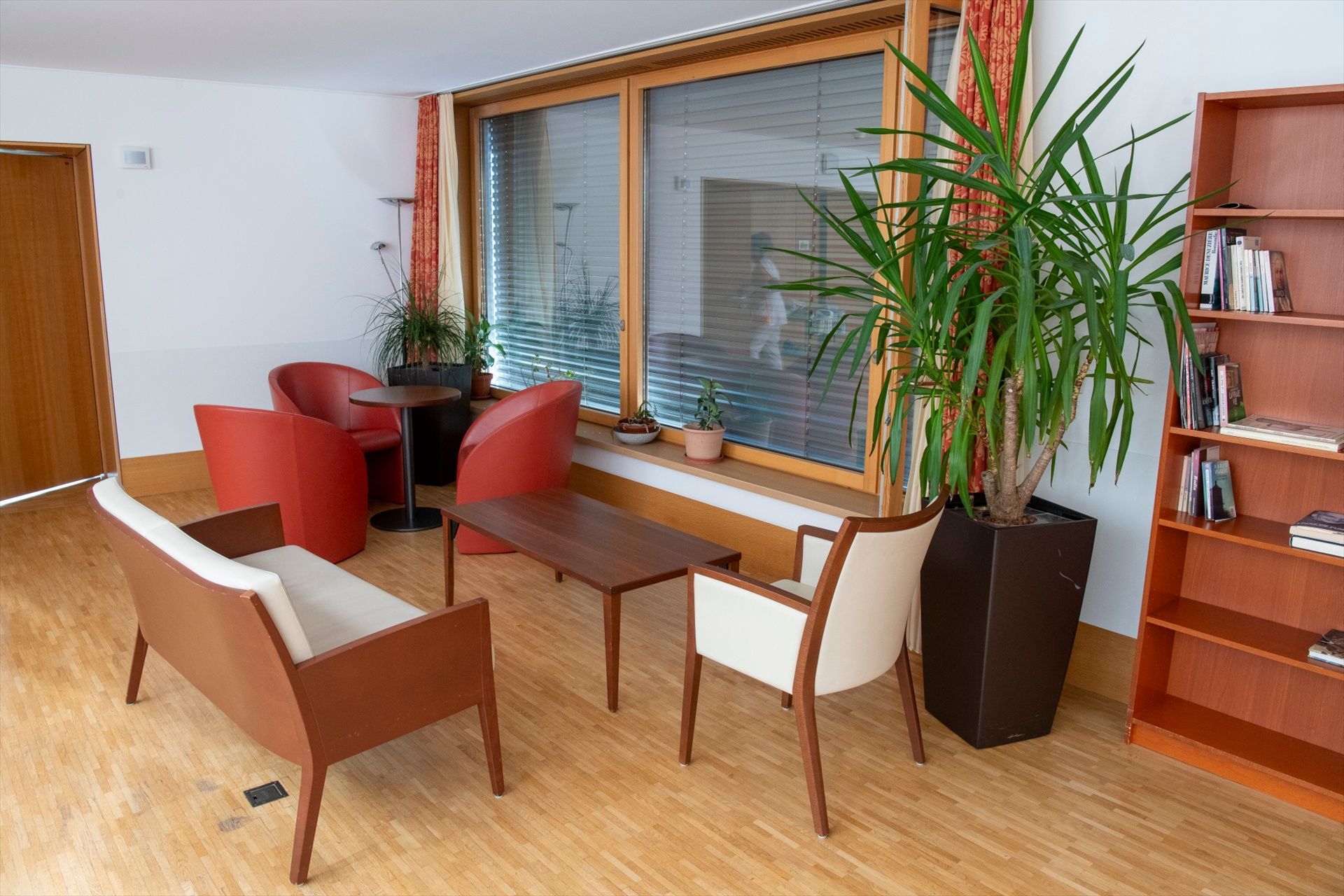 Un salon avec un canapé, des chaises, une table et une bibliothèque.