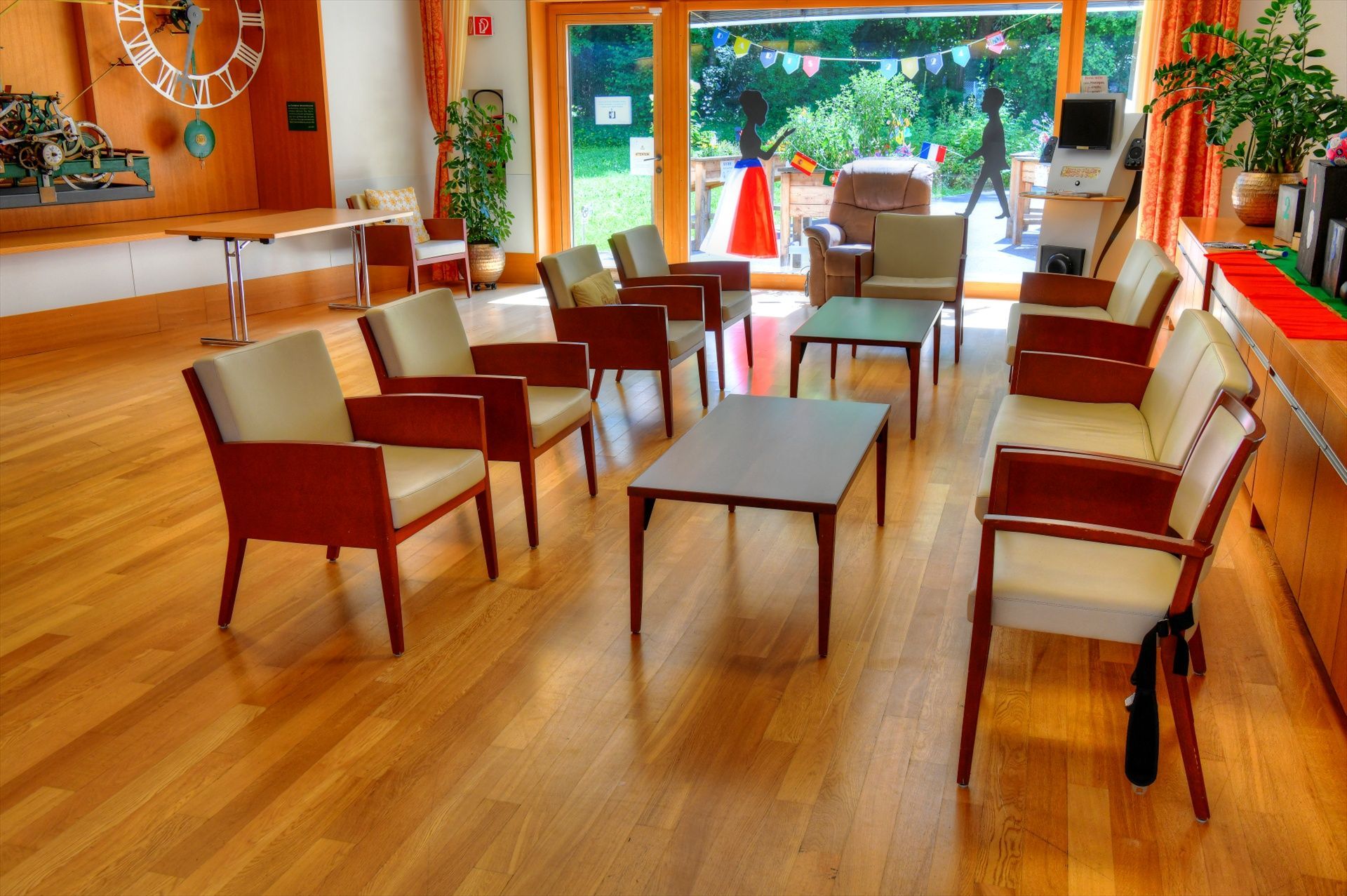 Un salon avec des chaises, des tables et une horloge au mur