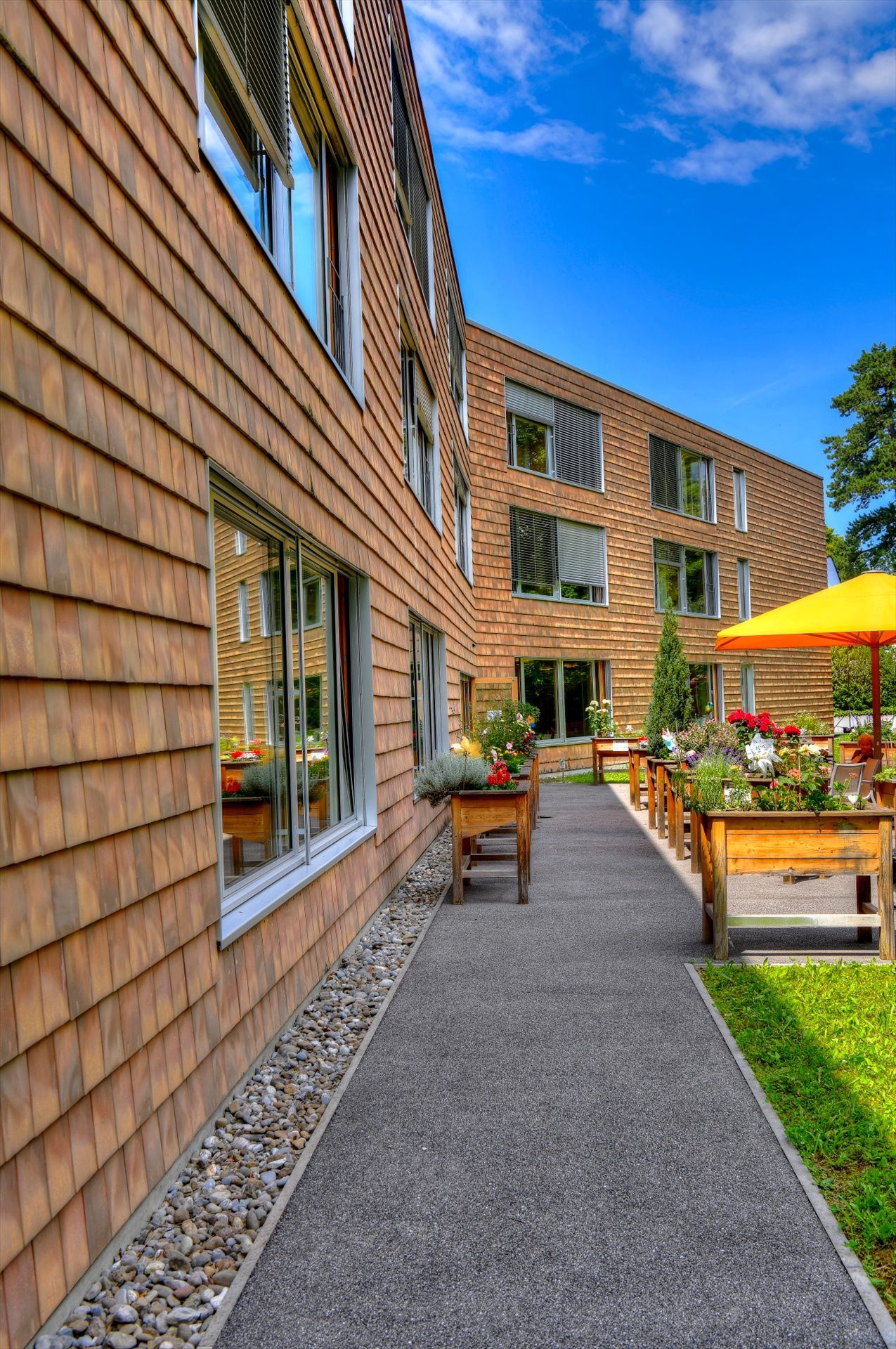 Une passerelle menant à un grand bâtiment avec un parapluie jaune.