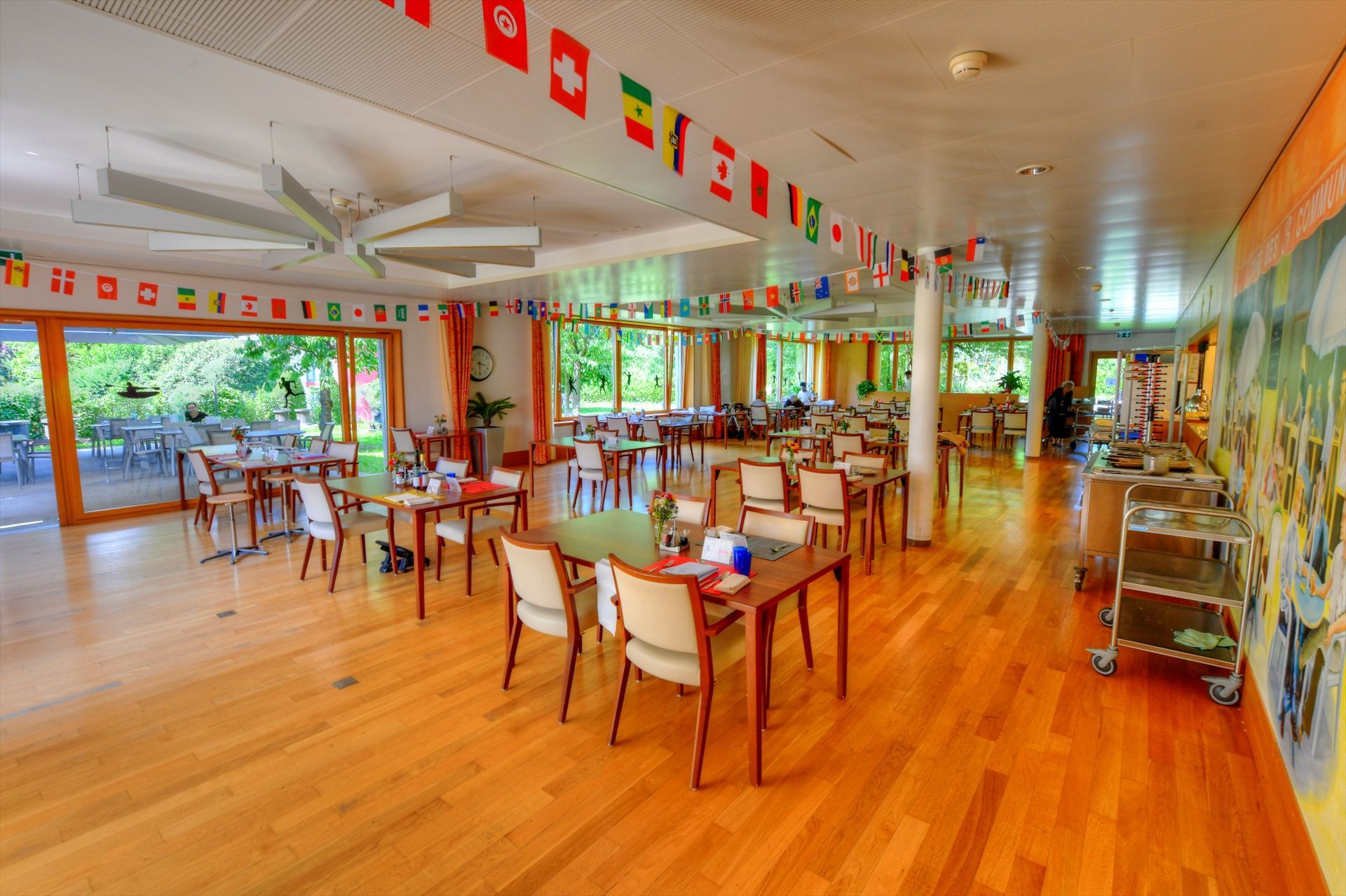 Une grande salle avec des tables et des chaises et des drapeaux suspendus au plafond