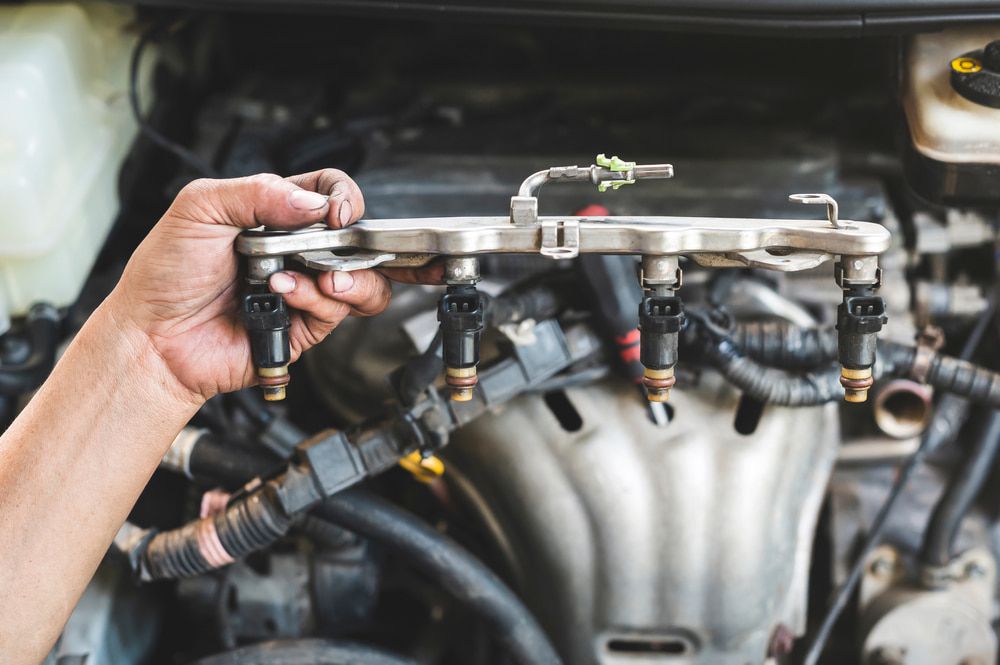 A Person is Holding a Fuel Injector in Front of a Car Engine — ANI Automotive in Long Jetty, NSW