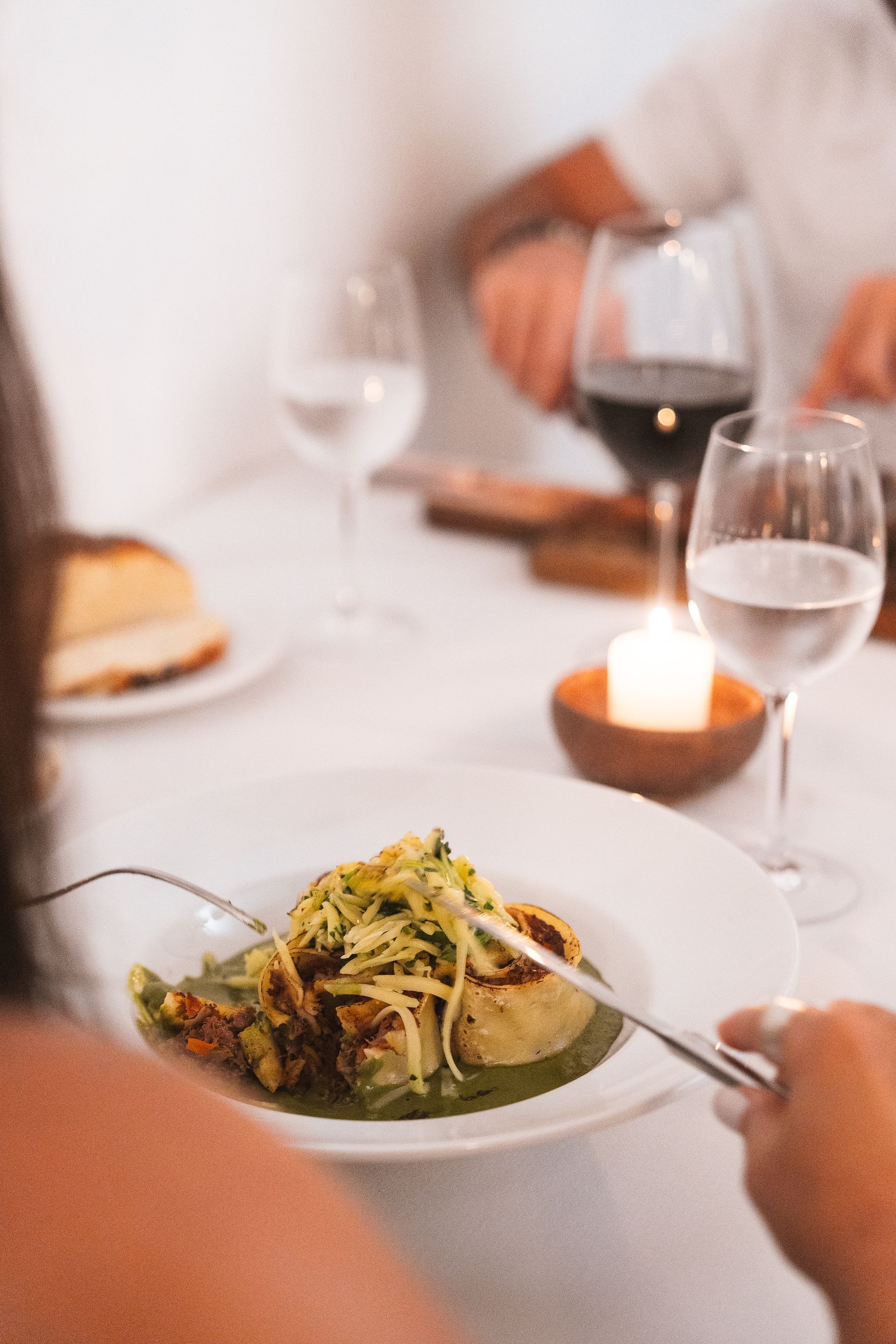 Un plato de sopa junto a una cuchara sobre una mesa