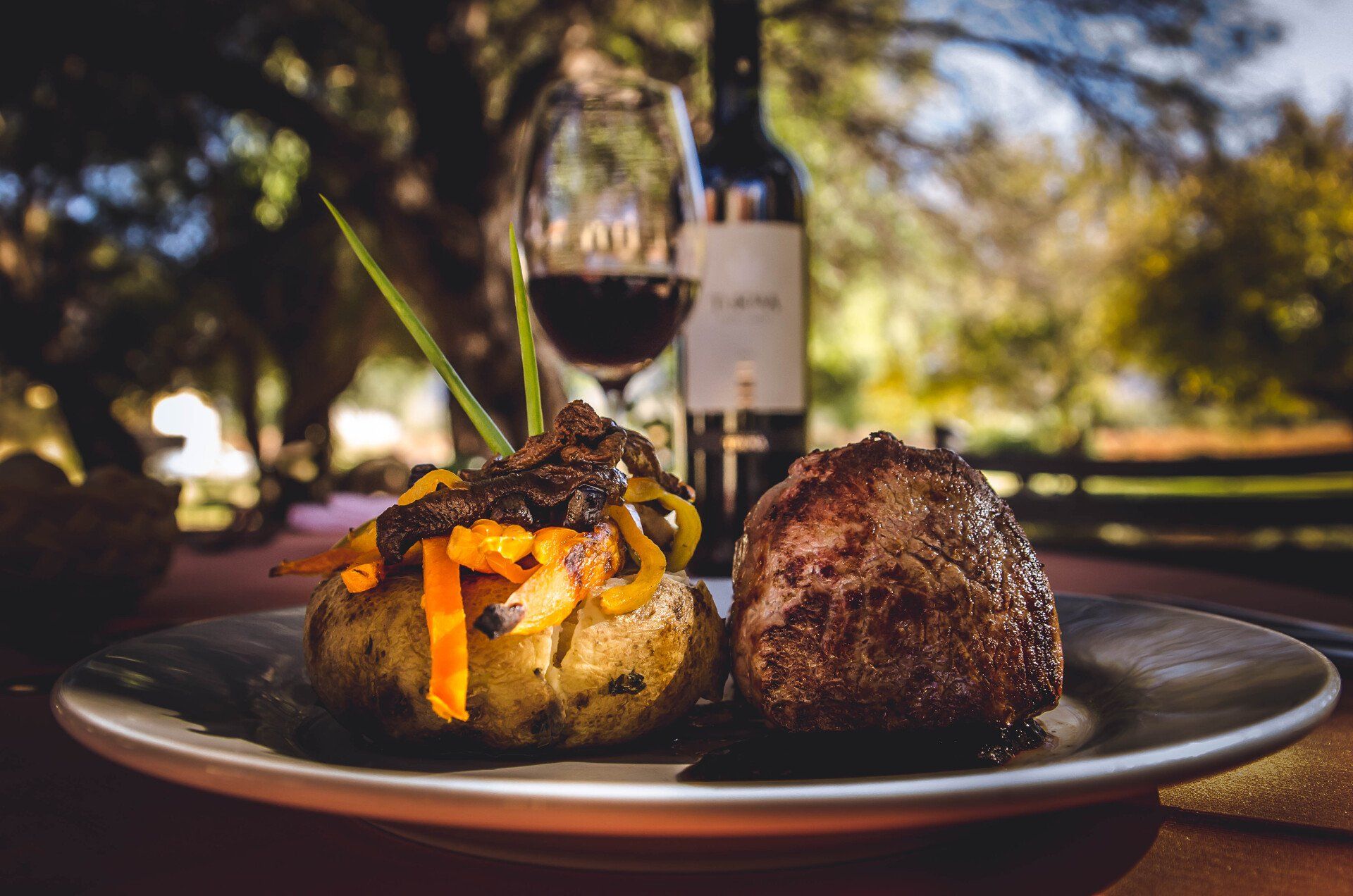 Un plato de comida y una copa de vino sobre una mesa.