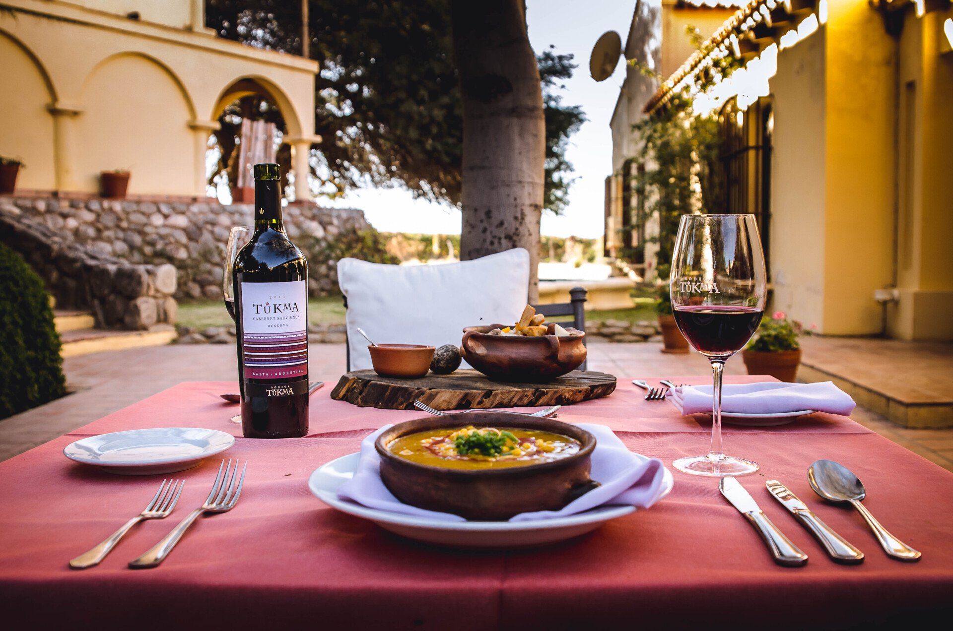 Hay una botella de vino sobre una mesa junto a un plato de sopa.