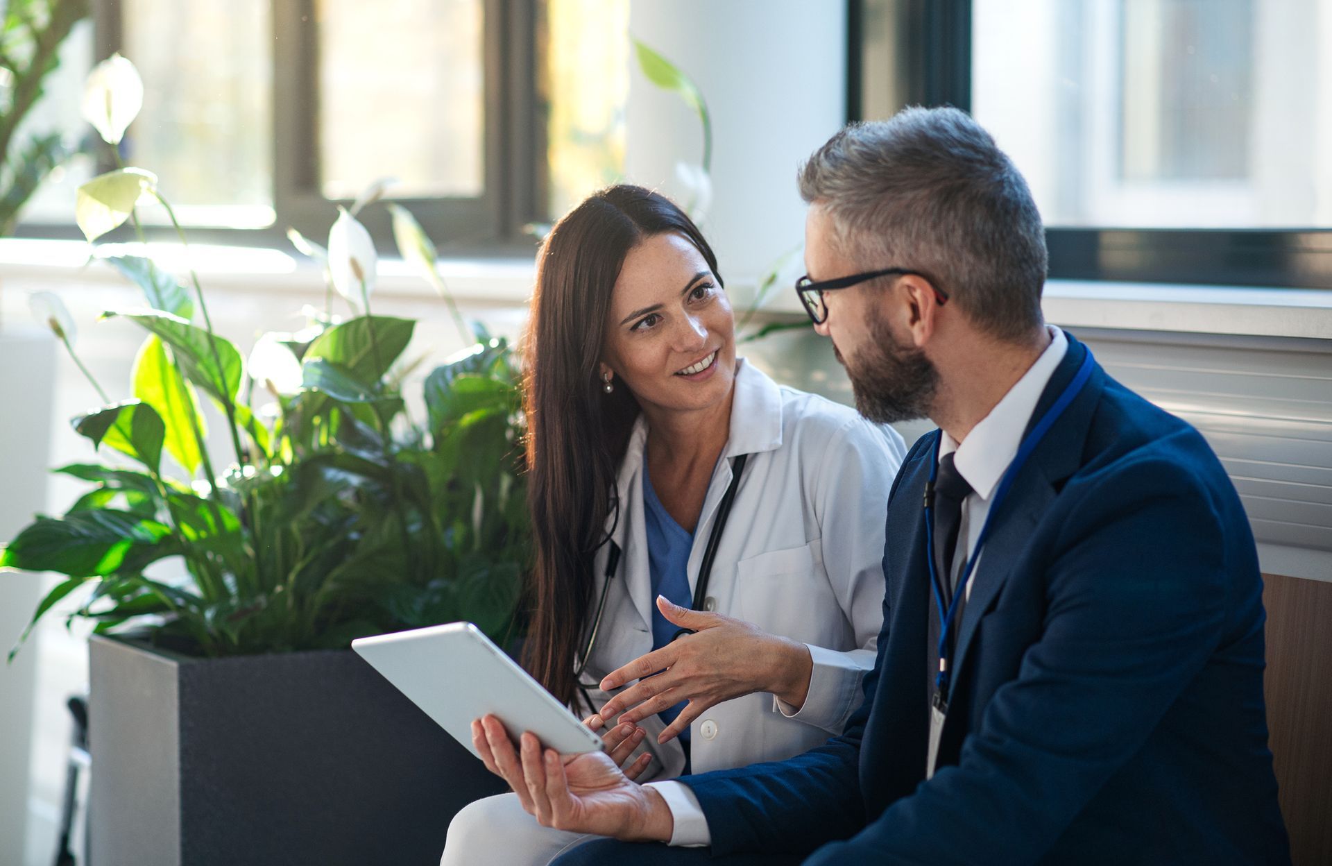 A man and a woman are sitting next to each other looking at a tablet.