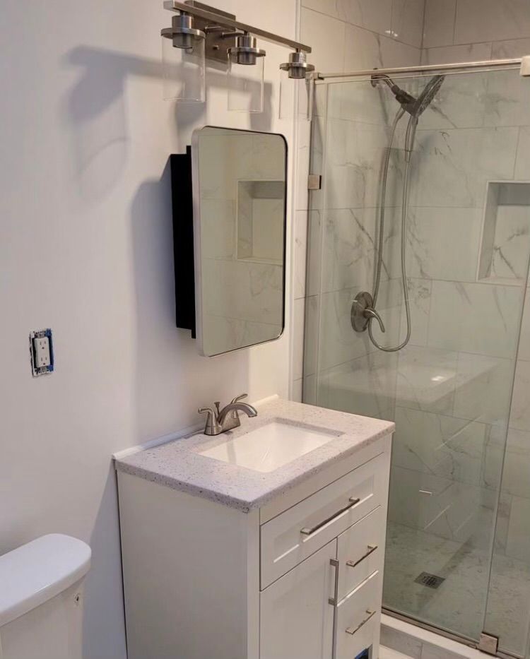 A bathroom with a sink , mirror , toilet and shower.
