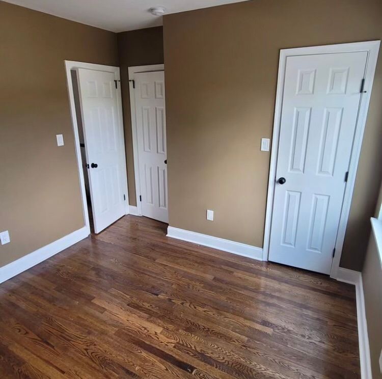 An empty room with hardwood floors and brown walls