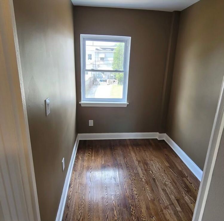 A small room with hardwood floors and a window.