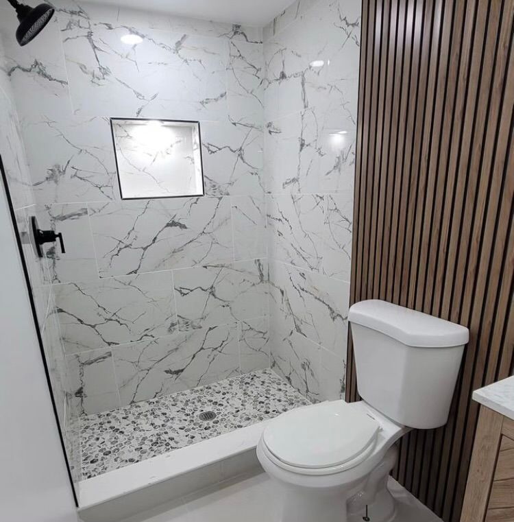 A bathroom with a toilet and shower with marble walls