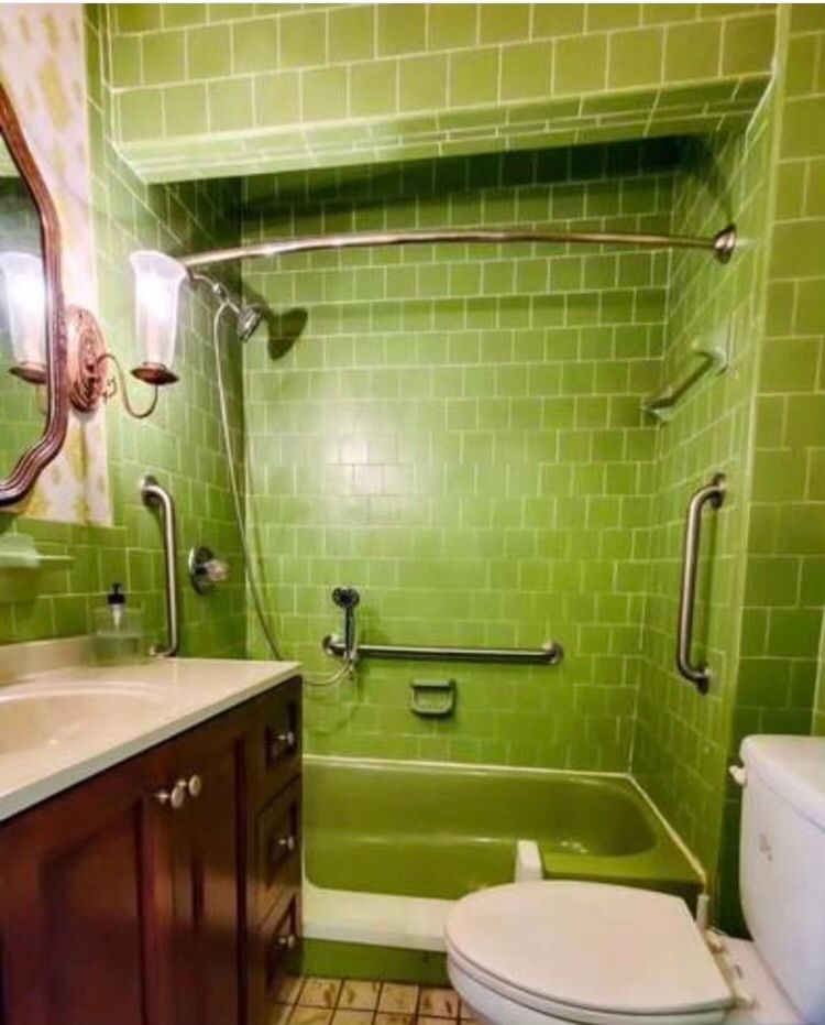 A bathroom with green tiles and a toilet different view