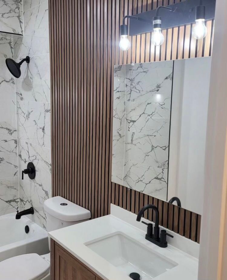 A bathroom with a sink , toilet , shower and mirror.