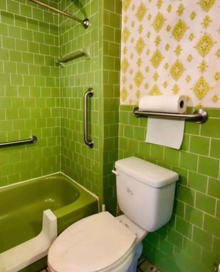 A bathroom with green tiles and a toilet