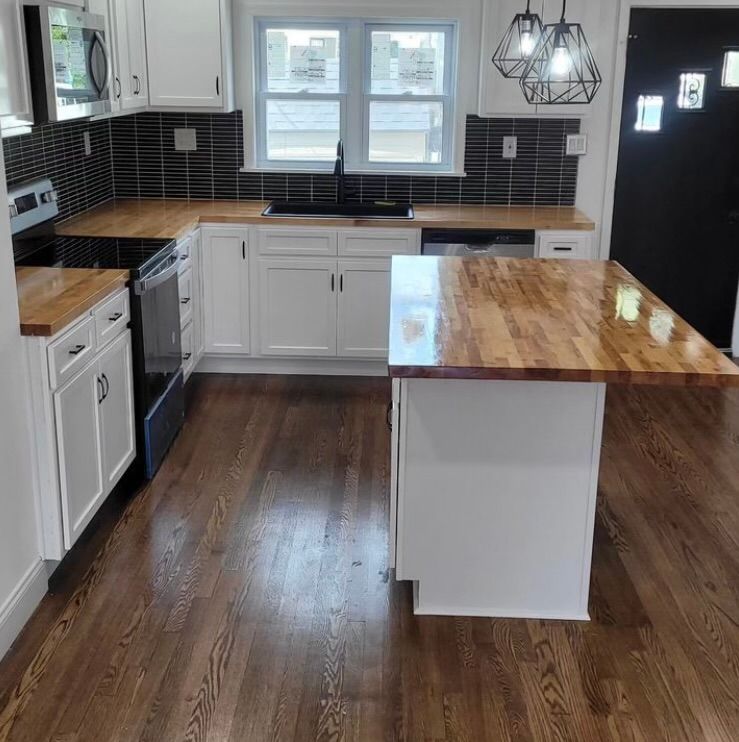 A kitchen with white cabinets and wooden counter tops