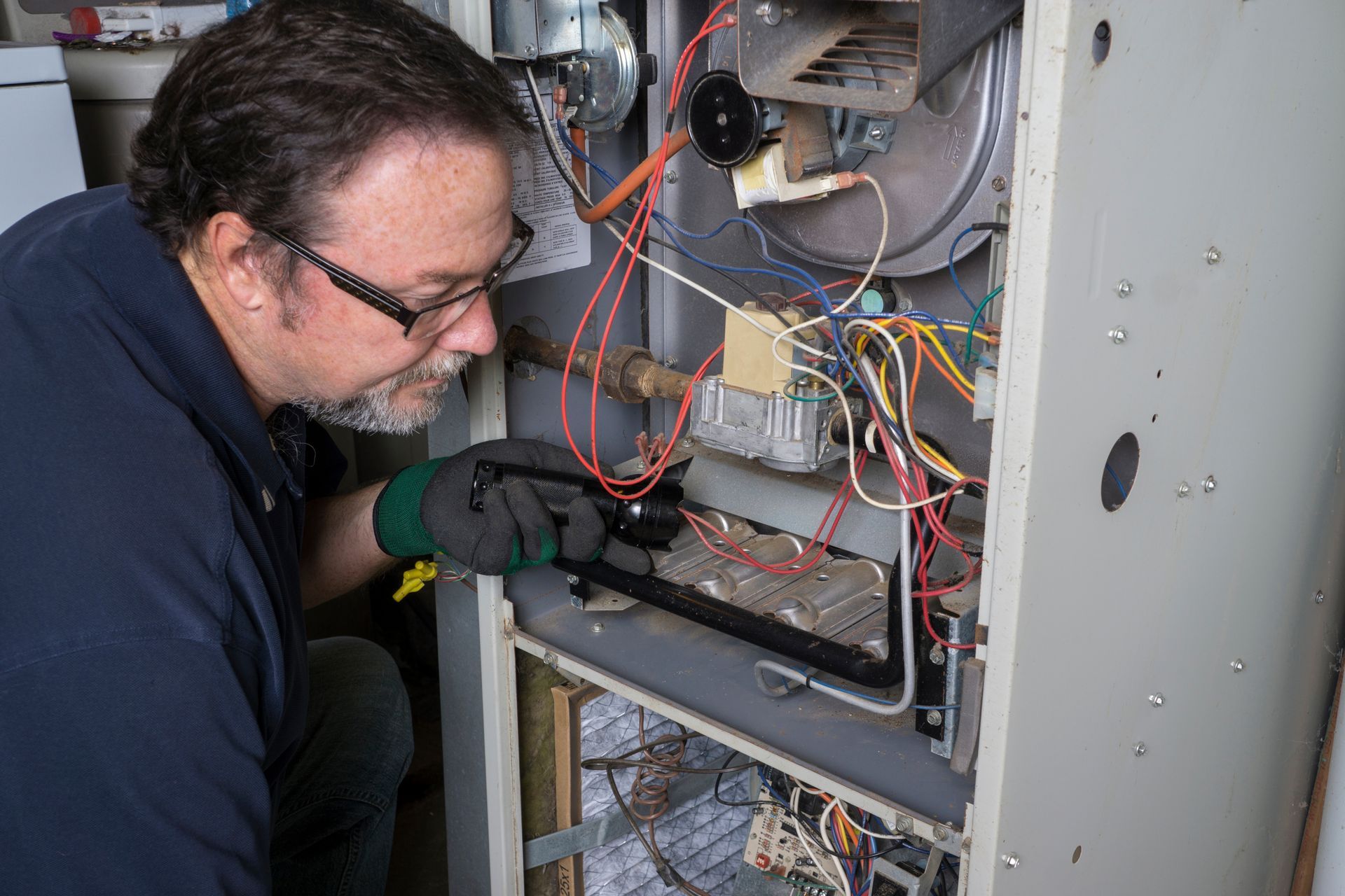 A man is inspecting a gas furnace.