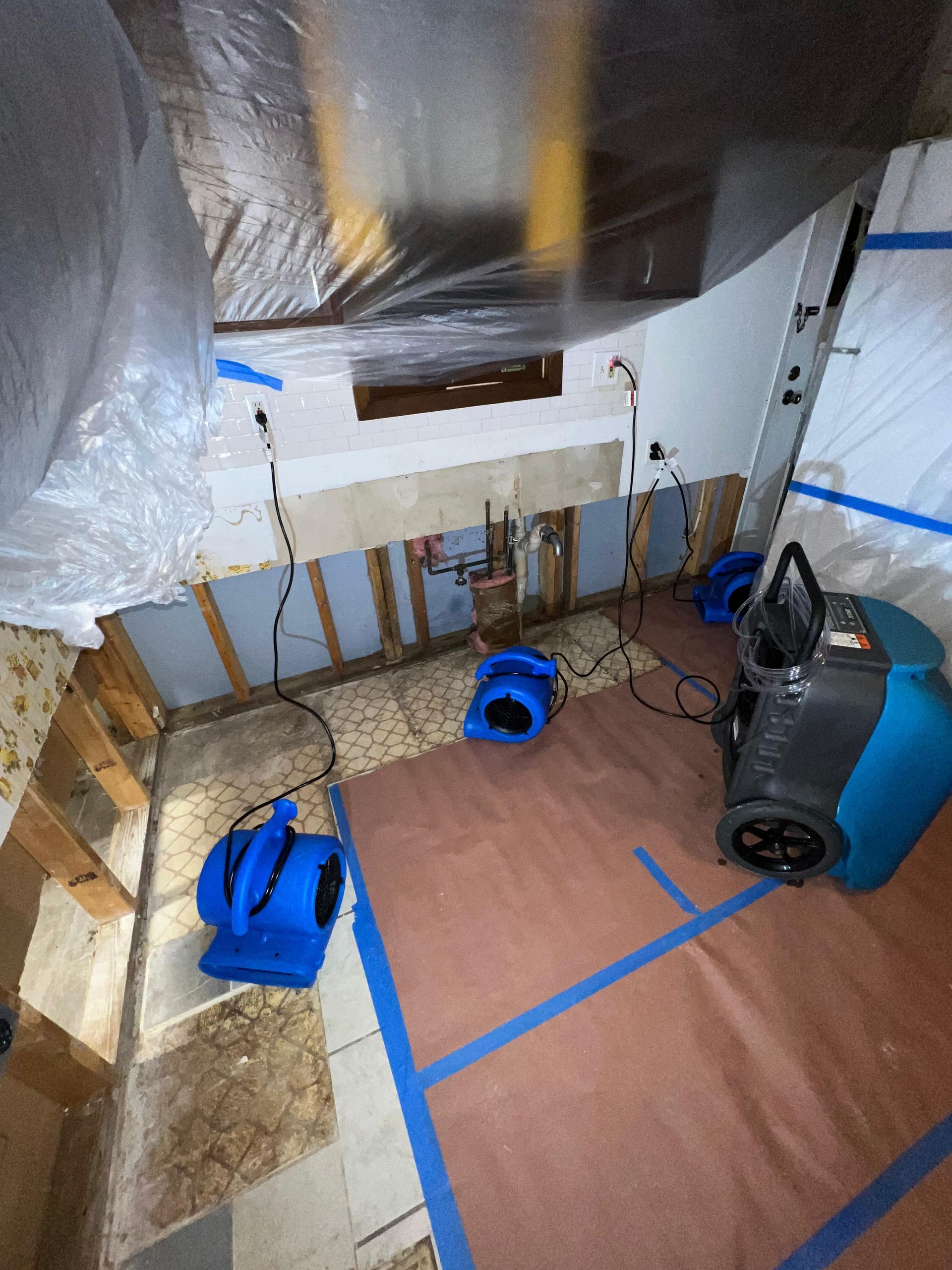 Basement workspace with insulation, ducting, taped floor area, and a vacuum system.