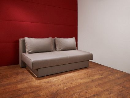 In einem Raum mit einer roten Wand steht ein Sofa.