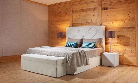 Ein Schlafzimmer mit Bett und dazugehörigem Kopfteil und Holzwänden.