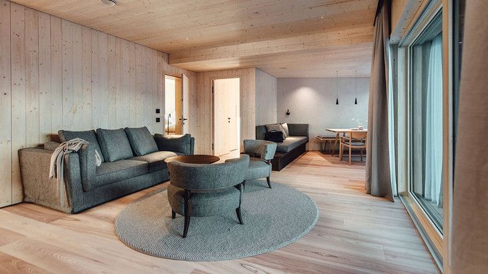 Ein Zimmer mit grauen Sofas, Stühlen und einem großen Fenster.