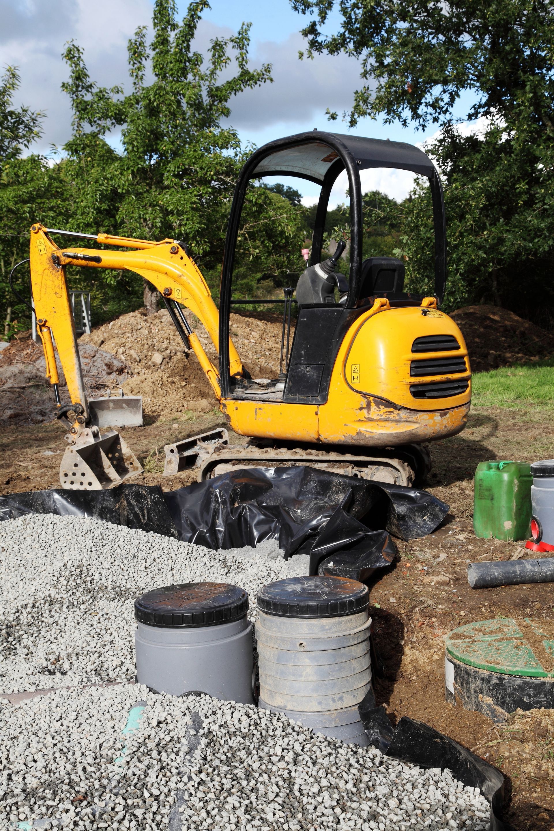 A yellow excavator is sitting on top of a pile of gravel.