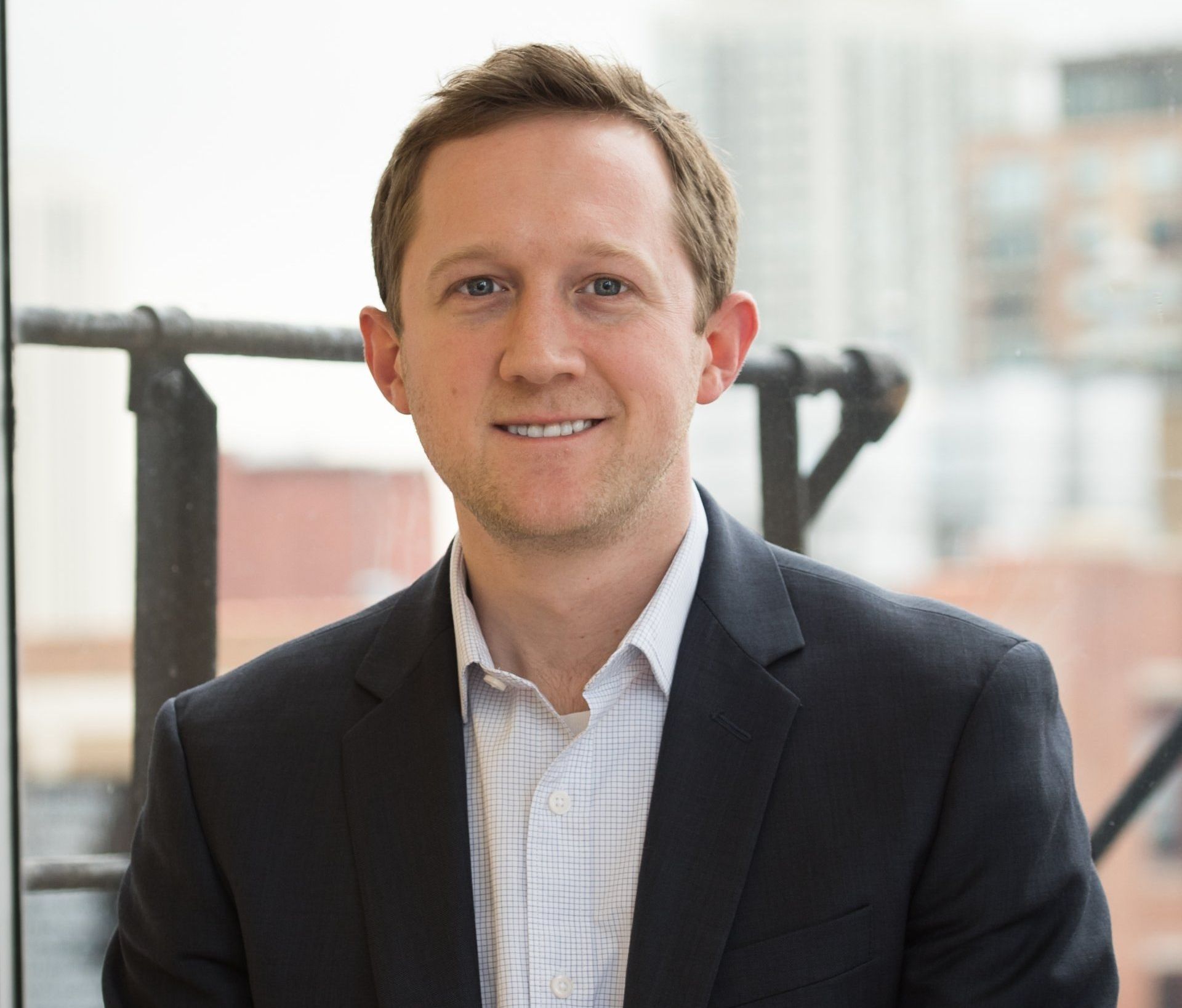 A man in a suit and white shirt is smiling for the camera