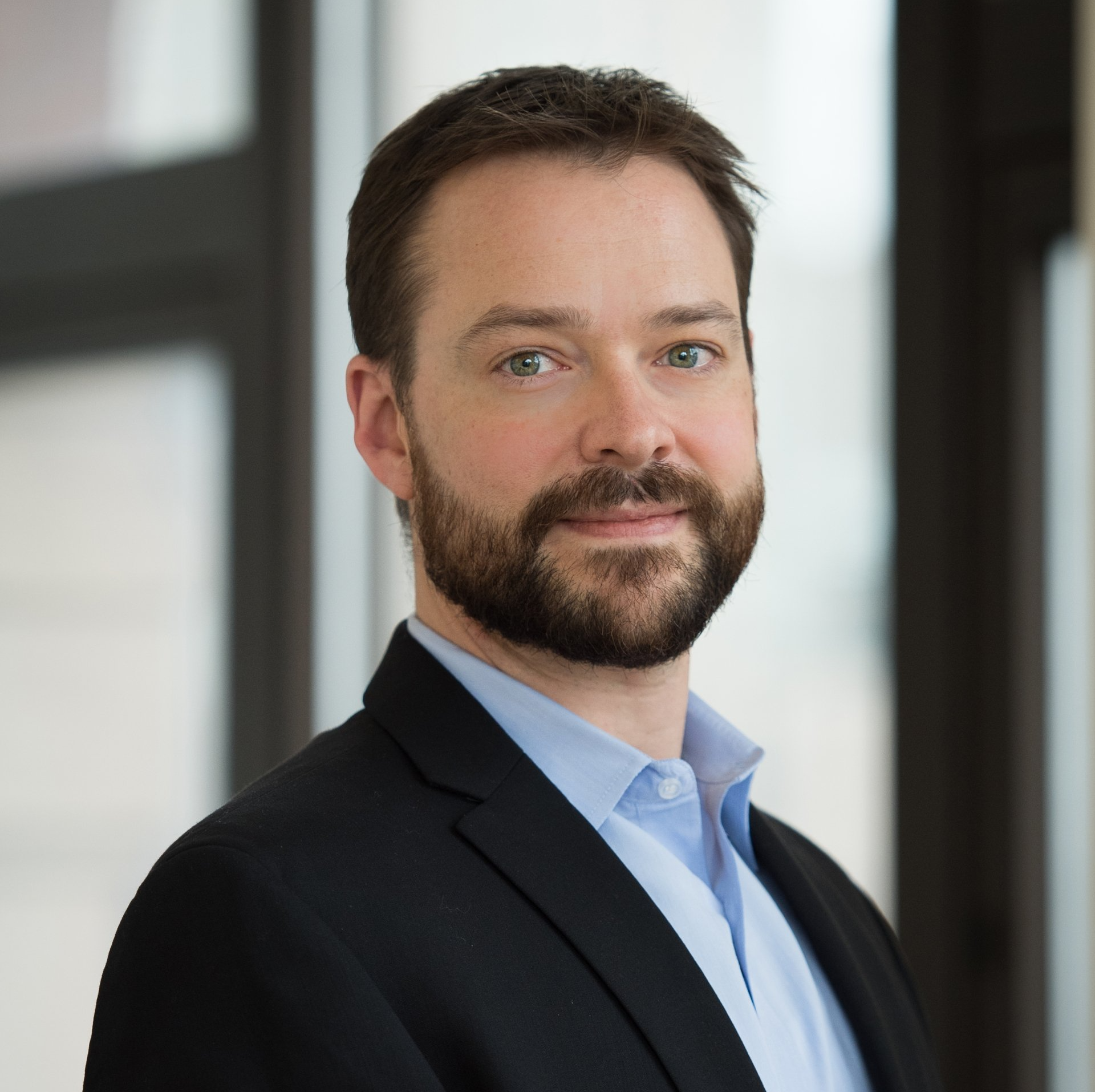 A man with a beard wearing a suit and blue shirt