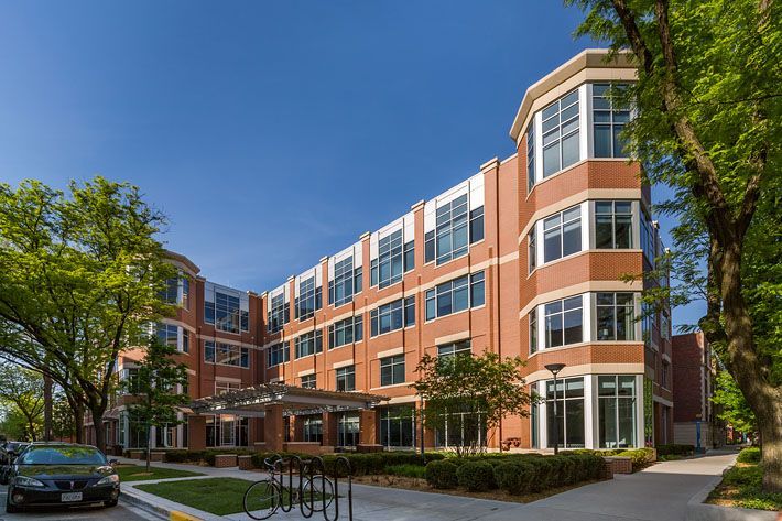 A large brick building with a lot of windows and a car parked in front of it.