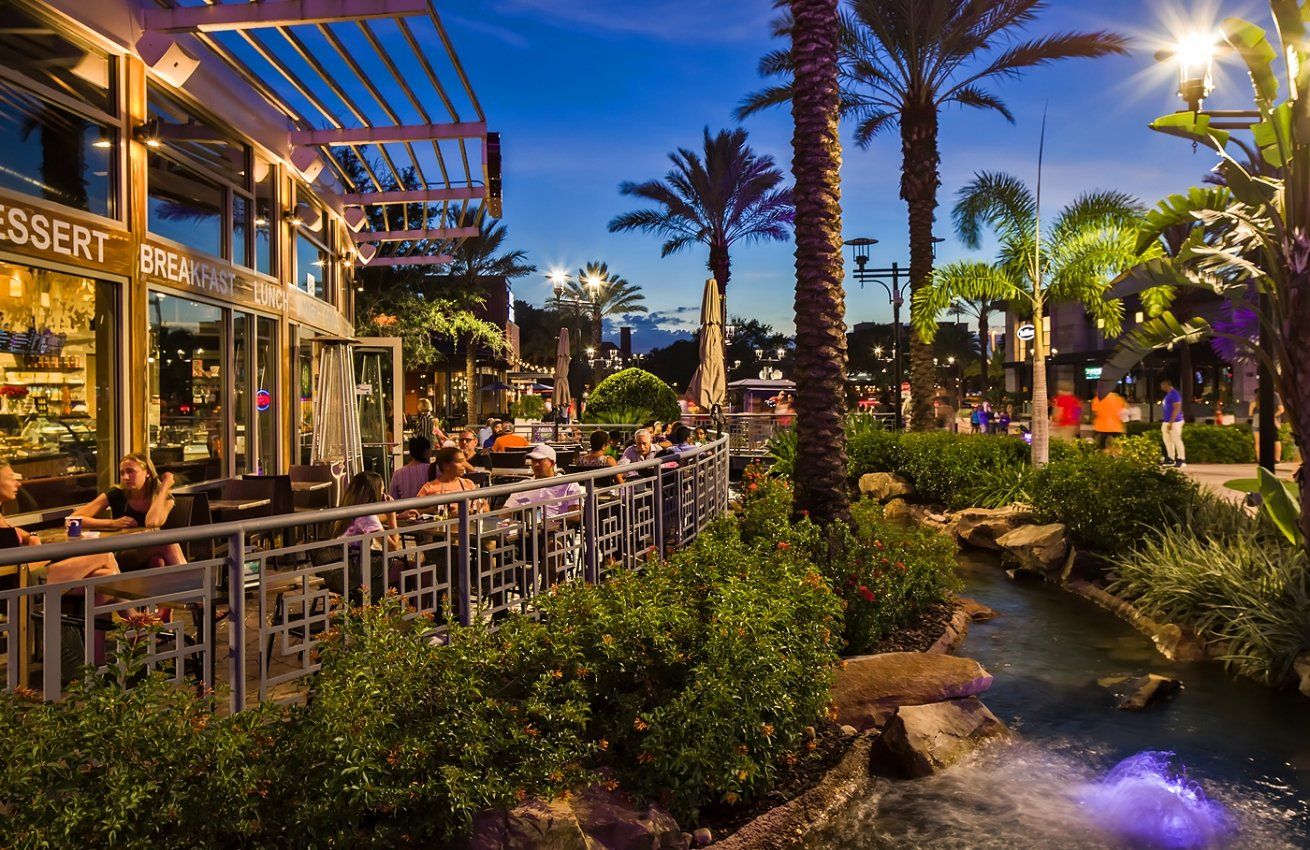 A group of people are sitting at tables outside of a restaurant.