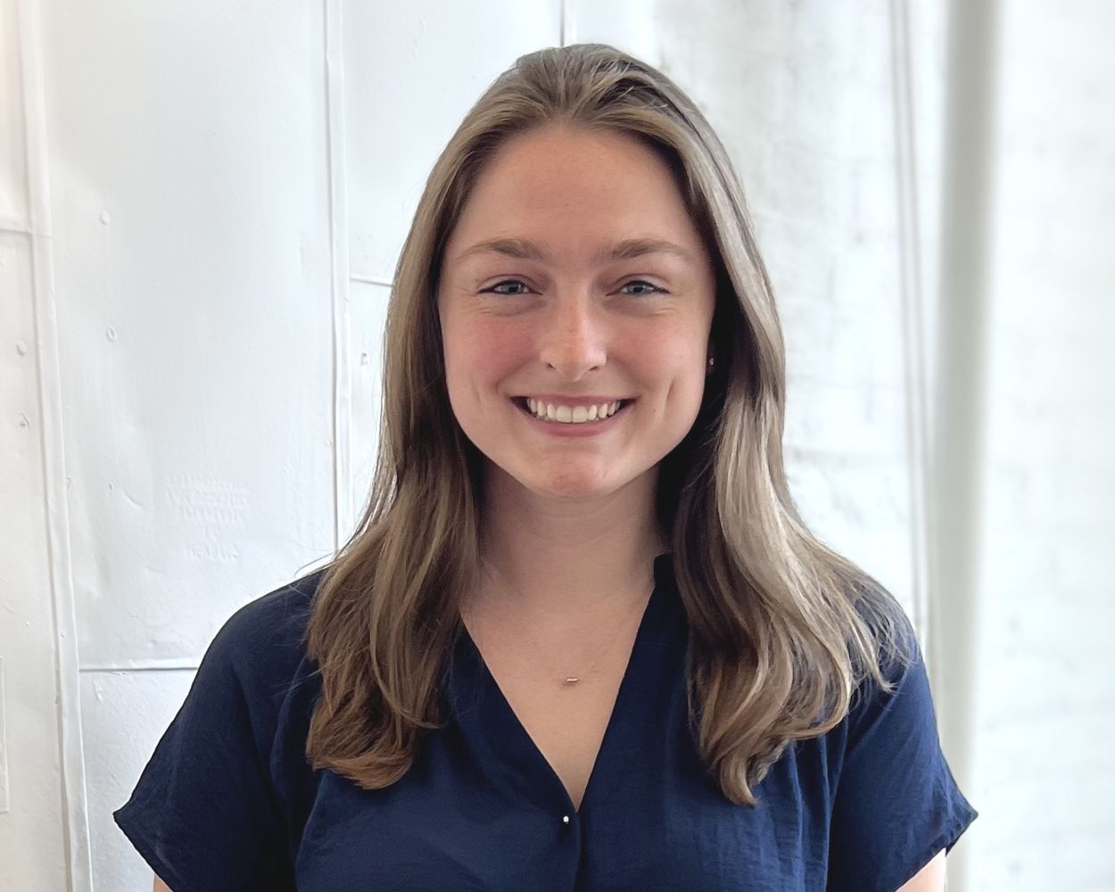 A woman in a blue shirt is smiling for the camera.