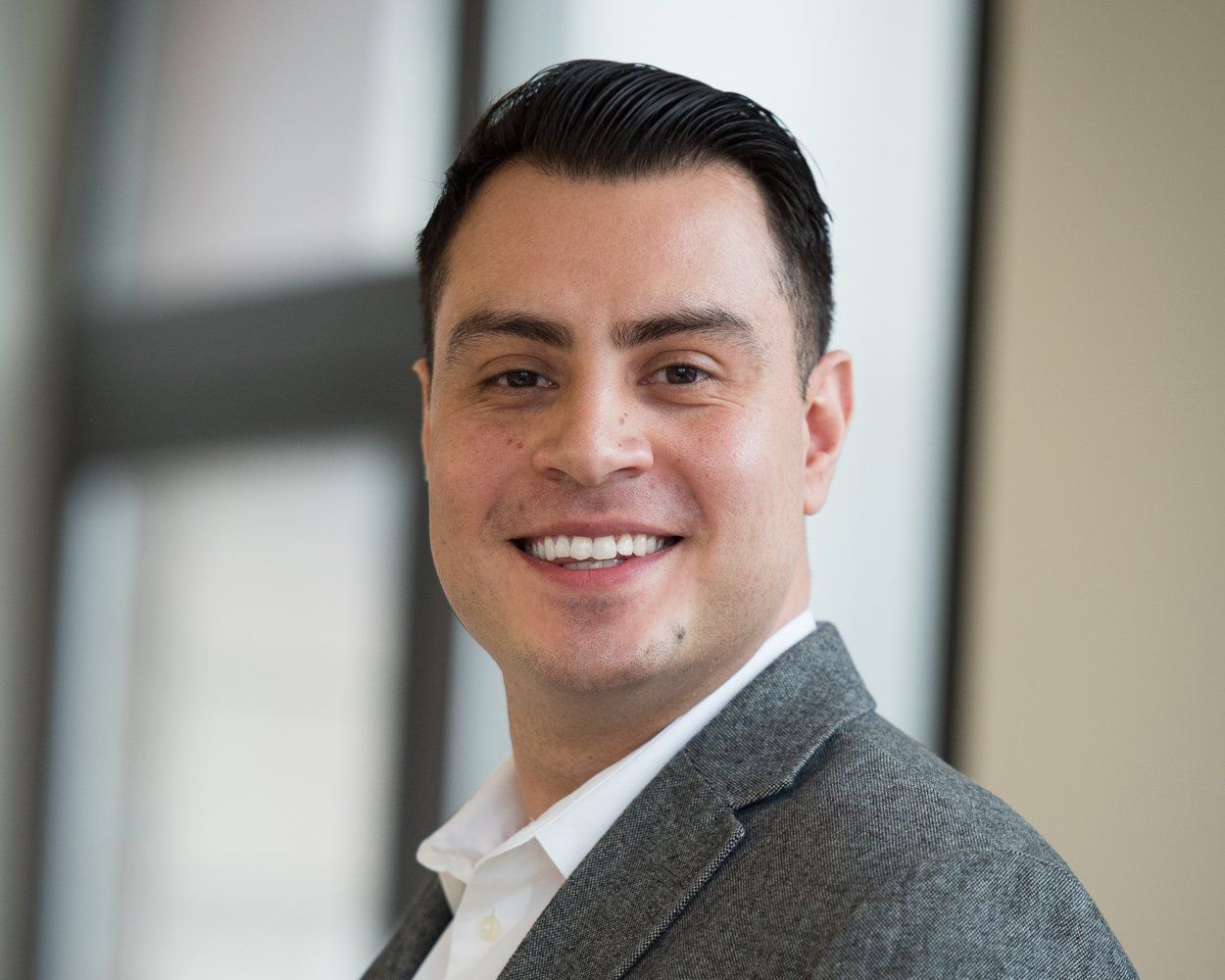 A man in a suit and white shirt is smiling for the camera.
