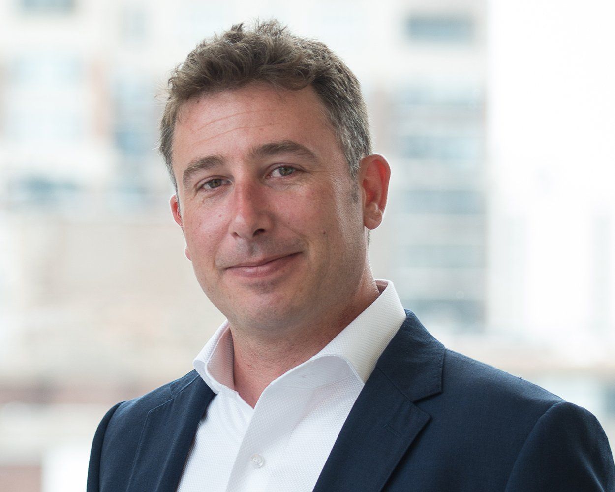 A man in a suit and white shirt is smiling for the camera.