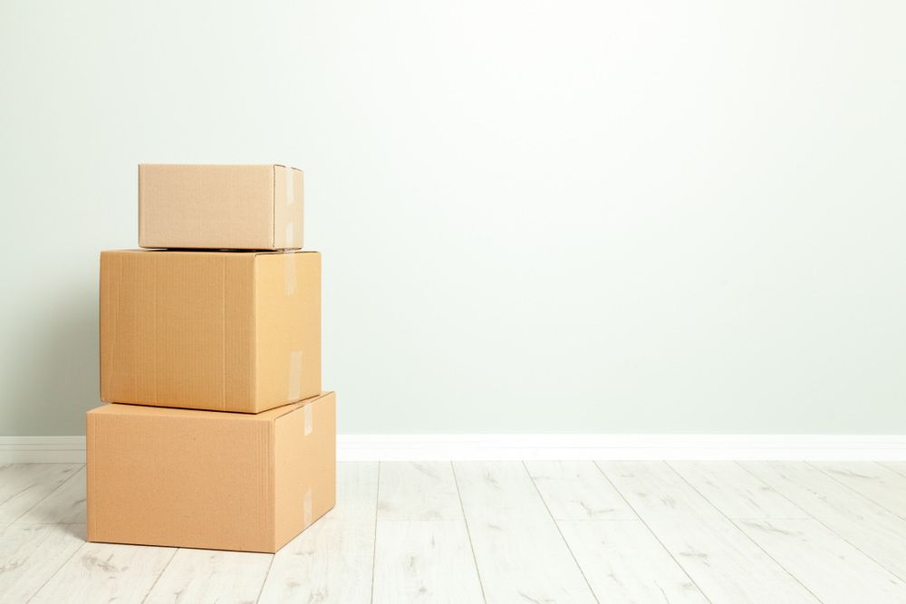 Three Cardboard Boxes Are Stacked On Top Of Each Other In An Empty Room — Removalists In Lismore