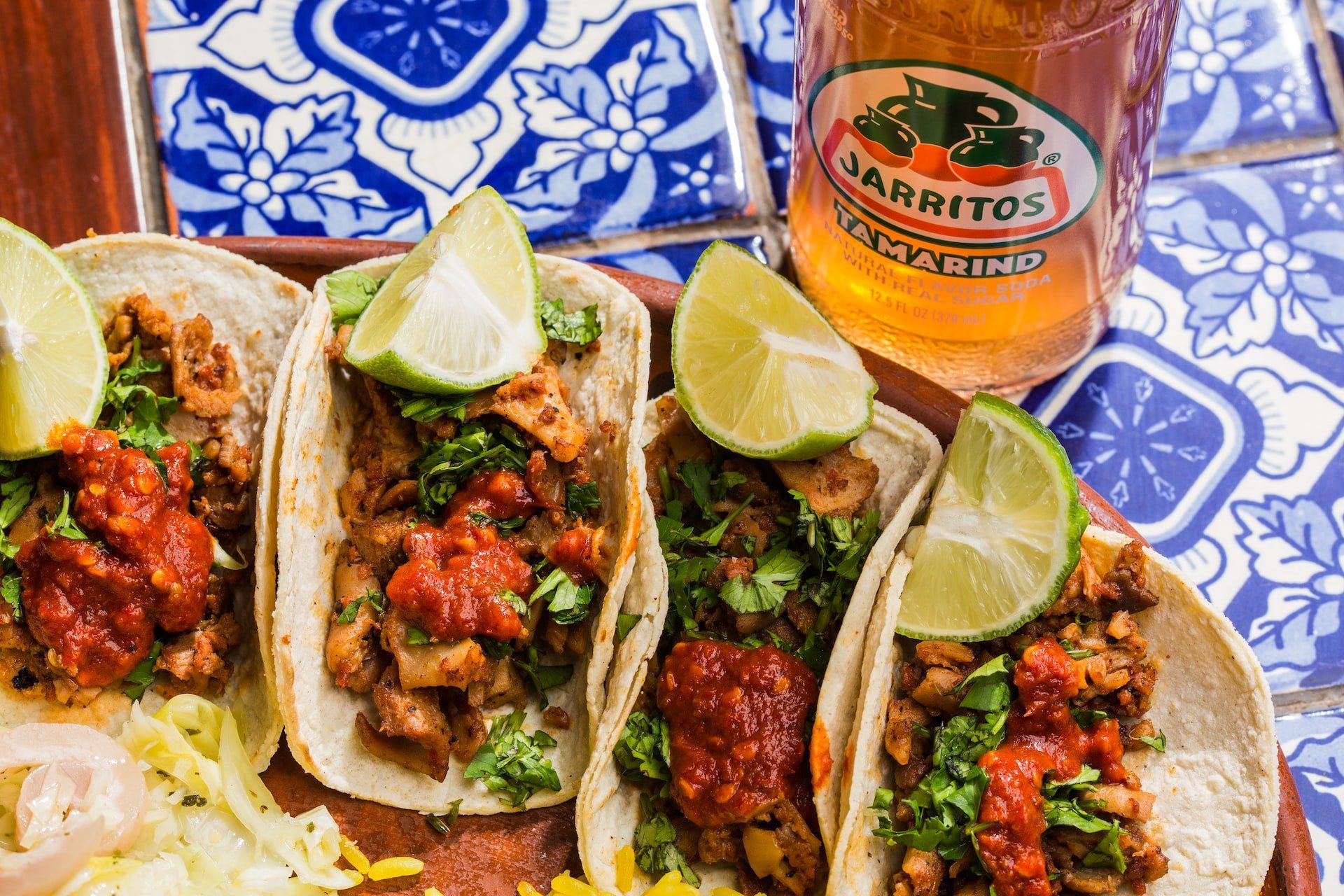 A close up of a plate of tacos next to a glass of beer.