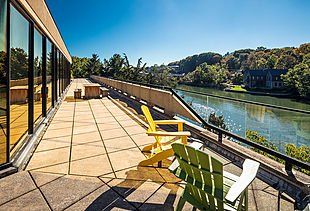 a patio with chairs and a table overlooking a river .
