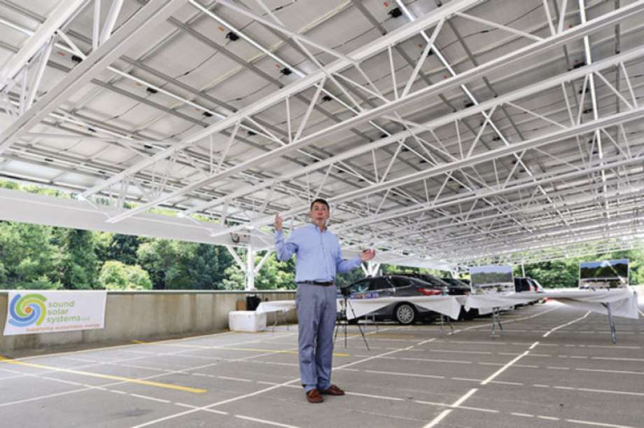 a man is standing in a parking garage with solar panels on the roof .