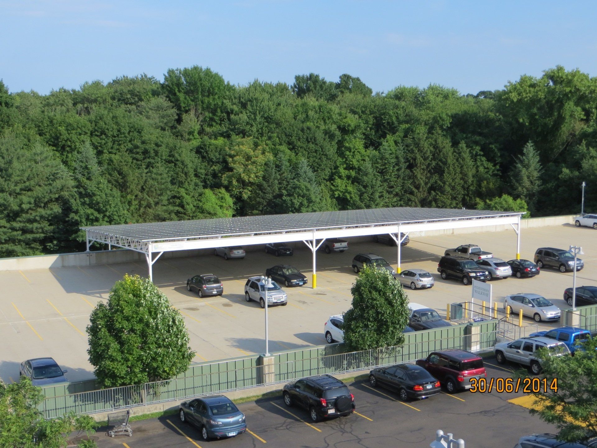a lot of cars are parked under a canopy in a parking lot .