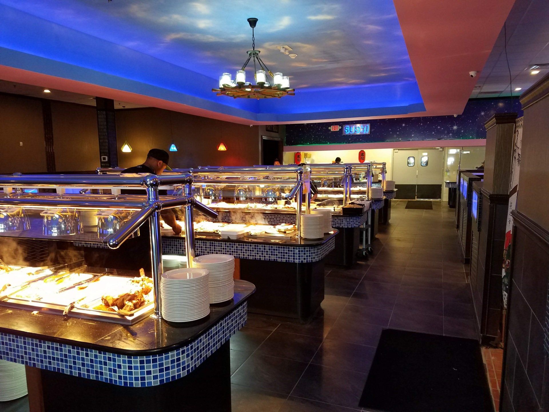 a buffet line in a restaurant with a chandelier hanging from the ceiling .