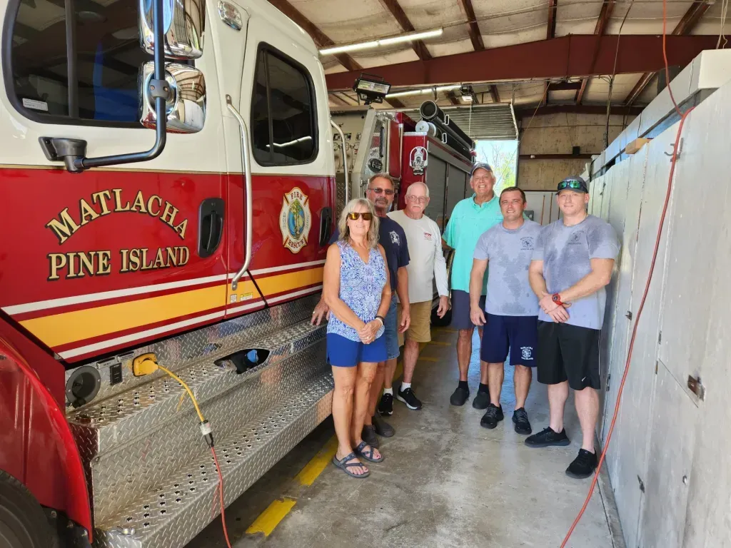 A group of people are standing in front of a fire truck.