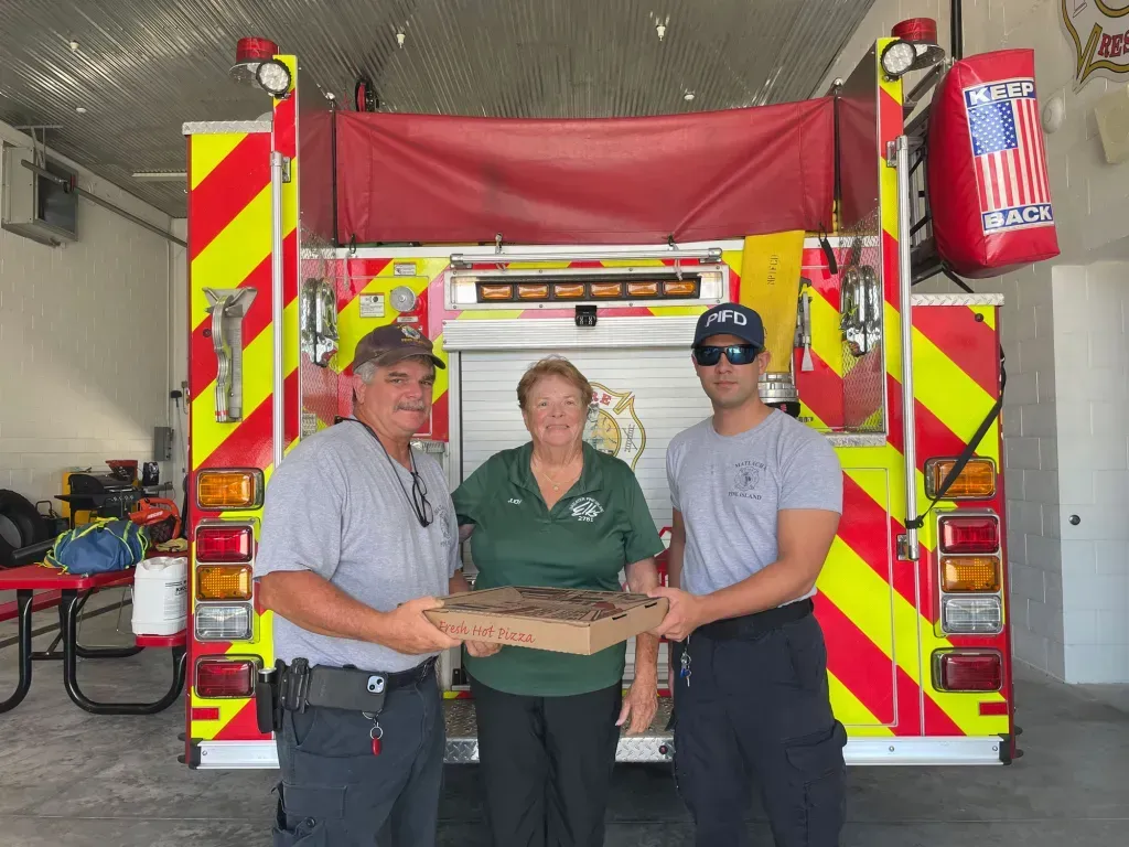 Two men and a woman are standing in front of a fire truck.