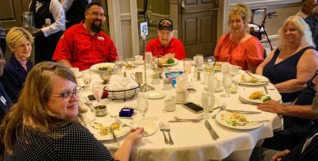 A group of people are sitting around a table with plates of food.