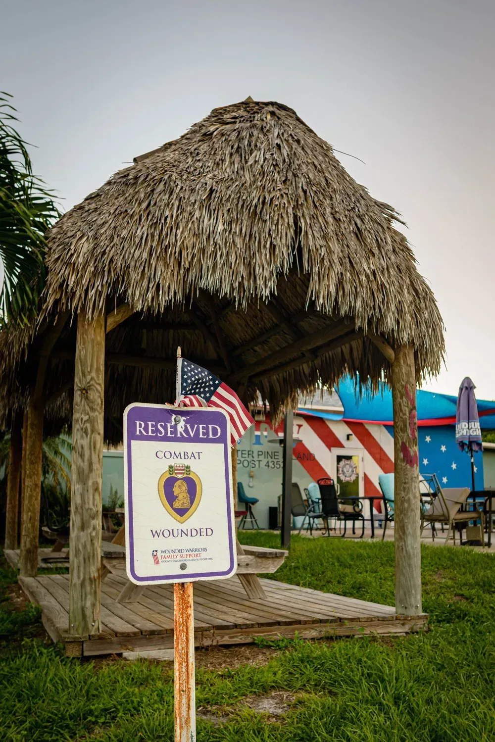 A thatched gazebo with a sign that says rest room in front of it.
